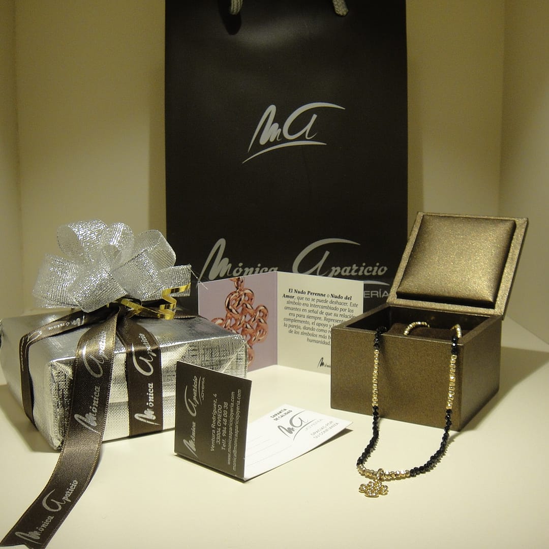 Conjunto de regalo con el colgante de oro Nudo Perenne en un precioso collar de espinelas negras y pirita, con su empaquetado cde regalo.